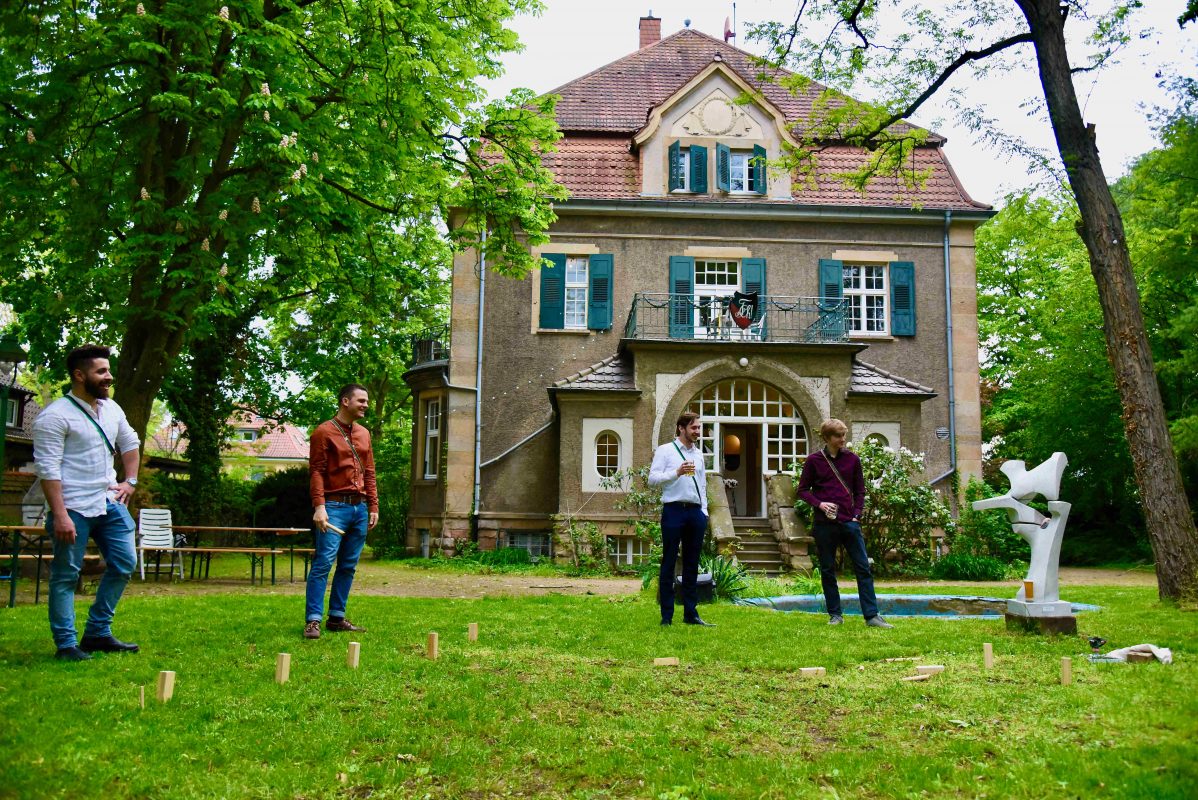 Das Corpshaus im Hintergrund. Im Vordergrund Mitglieder der Verbindung beim Spielen von Wikingerschach in einem schönen Garten.